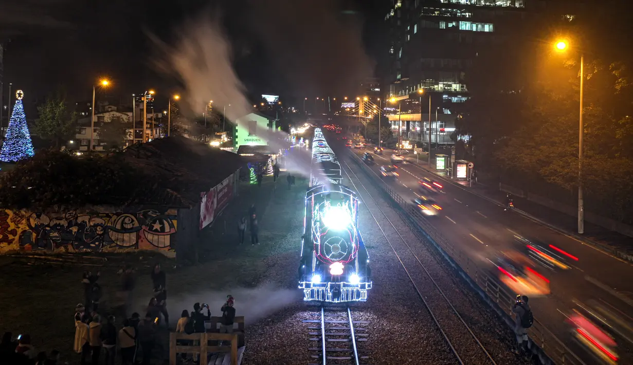 Kereta wisata yang dihiasi lampu Natal melintas membawa penumpang di Bogota (20/12/2019). Meyambut Hari Natal, kereta wisata di Kolombia membuat cara unik dengan memasangkan lampu warna-warni agar menjadi daya tarik penumpang. (AFP Photo/Juan Barreto)