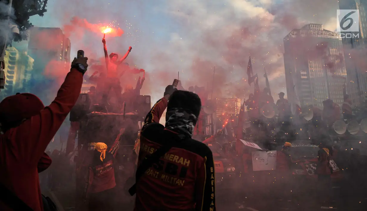 Sejumlah buruh menyalakan bom asap saat menutup aksi Hari Buruh Internasional di Jalan Medan Merdeka Barat, Jakarta, Rabu (5/1/2019). Buruh dari berbagai organisasi merayakan Hari Buruh Internasional di Kawasan Silang Barat Daya Monas. (merdeka.com/Iqbal S Nugroho)