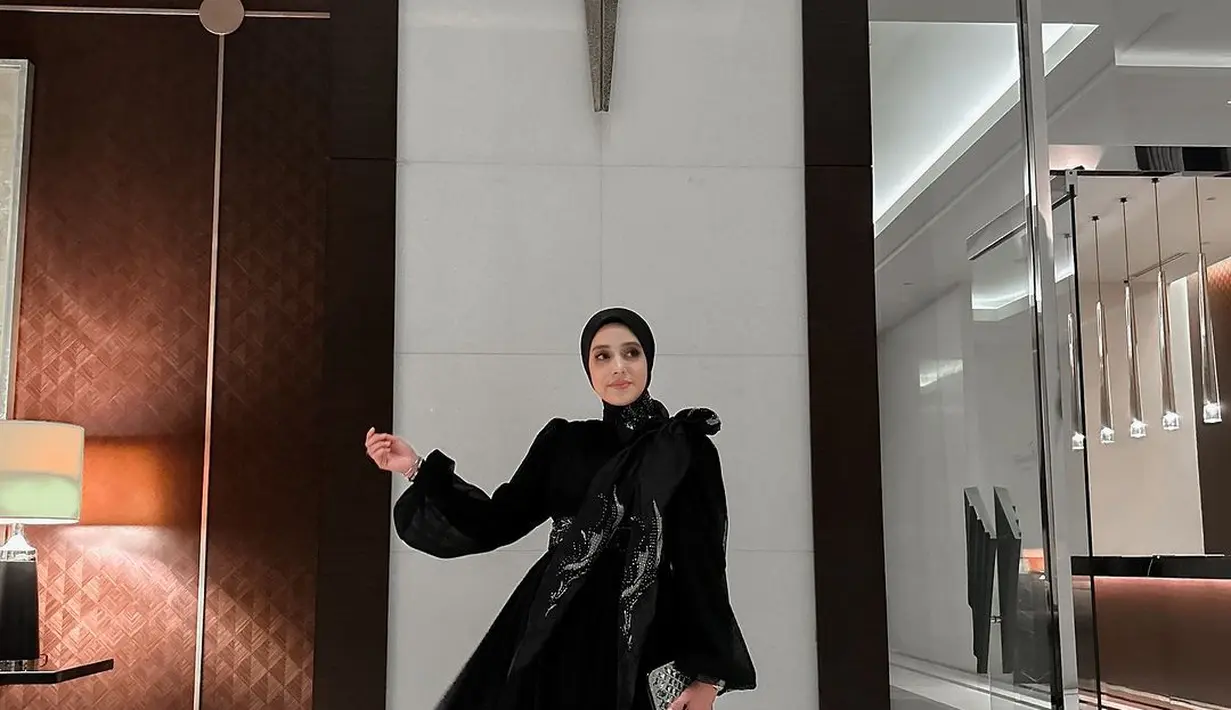 Sementara saat momen resepsi, Fairuz A Rafiq menunjukkan pesona elegan dalam balutan maxi dress dan hijab serba hitam. [@fairuzarafiq].