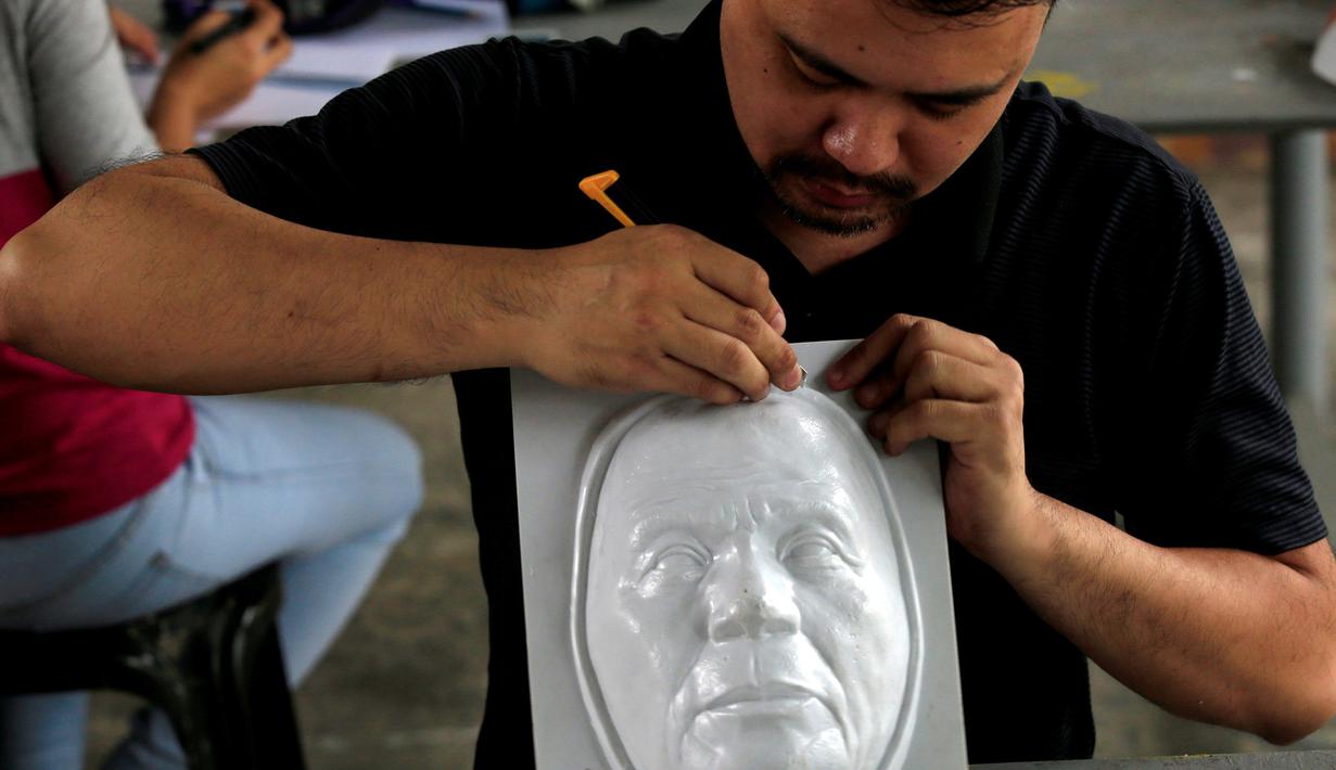 Mahasiswa saat membuat topeng Presiden Rodrigo Duterte untuk perayaan Halloween di Universitas Filipina, Kota Quezon, Filipina (13/10). Duterte saat ini menjadi sosok paling populer di Filipina karena berbagai kontroversinya. (REUTERS/Romeo Ranoco) 