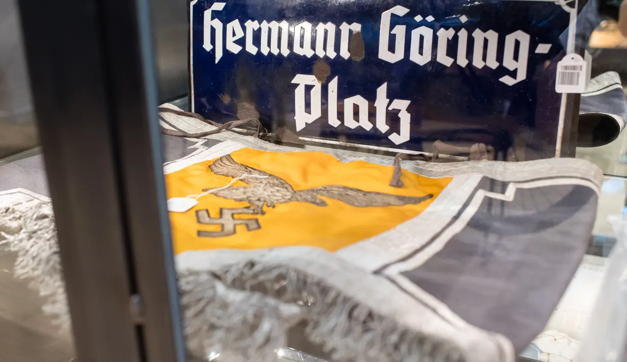 Pelat bertuliskan 'Hermann Goering-Platz' dan hiasan genderang bergambar swastika ditampilkan sebelum lelang memorabilia Nazi di Grasbrunn, Jerman, Rabu (20/11/2019). Barang pribadi milik para petinggi Nazi saat Perang Dunia II ikut dilelang pada lelang kali ini. (Matthias Balk/dpa/AFP)