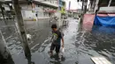 Warga berjalan ditengah banjir usai topan Nock-Ten menerjang kota Quezon, utara Manila, Filipina, (26/12). Topan super Nock-ten atau dikenal dengan Nina menerjang Filipina bertepatan saat Natal. (AP Photo / Aaron Favila)