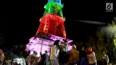 Warga berfoto dekat Pakaya Tower di kawasan taman Limboto, Kabupaten Gorontalo, Sabtu (12/1). Pakaya Tower berdiri megah bak Menara Eiffel dengan tata lampu warna-warni. (Liputan6.com/Arfandi Ibrahim)