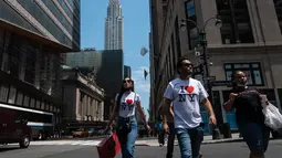 Orang-orang berjalan melewati Gedung Chrysler pada hari yang hangat di New York City (7/6/2021). Cuaca yang hangat di New York dimanfaatkan warga untuk membaca buku hingga berjalan-jalan. (AFP/Angela Weiss)