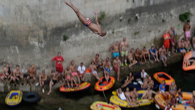 Penonton menyaksikan seorang peserta melompat dari Jembatan Old Mostar pada kompetisi menyelam tradisional ke-452 di Mostar, Bosnia, 29 Juli 2018. Kontes ini  sukses menarik 40 peserta lokal dan internasional dan penonton beberapa ribu. (AP/Amel Emric)