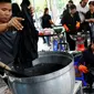 Relawan mewarnai pakaian pelayat agar menjadi hitam untuk dikenakan selama masa berkabung atas wafatnya raja Thailand Bhumibol Adulyadej di Grand Palace di Bangkok, Thailand (17/10). Relawan ini mewarnai pakaian warga secara suka rela.(Reuters/Edgar Su)