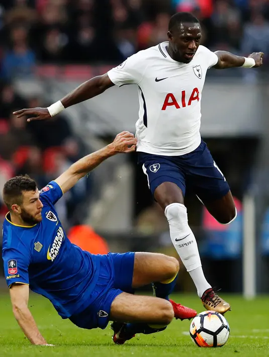 Pemain Tottenham Hotspur, Moussa Sissoko dan bek Wimbledon, Jonathan Meades berebut bola pada pertandingan putaran ketiga FA Cup di Stadion Wembley, Minggu (7/1). Tottenham Hotspur menyarangkan tiga gol tanpa balas ke gawang Wimbledon. (Adrian DENNIS/AFP)