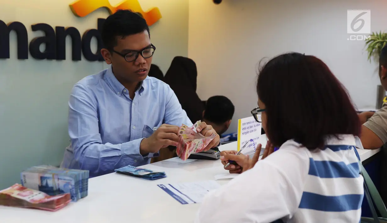 Petugas melayani transaksi setoran nasabah di cabang Bank Mandiri Pertamina UPMS III, Jakarta, Rabu (28/6). Bank Mandiri beroperasi secara terbatas untuk melayani nasabah pada musim liburan Idul Fitri 26-30 Juni 2017. (Liputan6.com/Angga Yuniar)