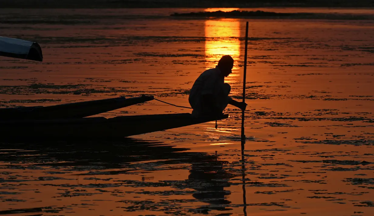 Seorang nelayan Kashmir berada di perahu saat matahari terbenam di danau Dal di Srinagar, India (12/9). Danau terbesar kedua di propinsi Jammu dan Kashmir ini  merupakan pusat pariwisata dan rekreasi. (AFP Photo/Tauseef Mustafa)