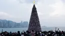 Orang-orang mengambil foto pohon Natal raksasa selama Natal di distrik budaya West Kowloon di Hong Kong (25/12/2021). Pohon Natal raksasa ini memiliki ukuran setinggi 20 meter. (AFP/Bertha Wang)