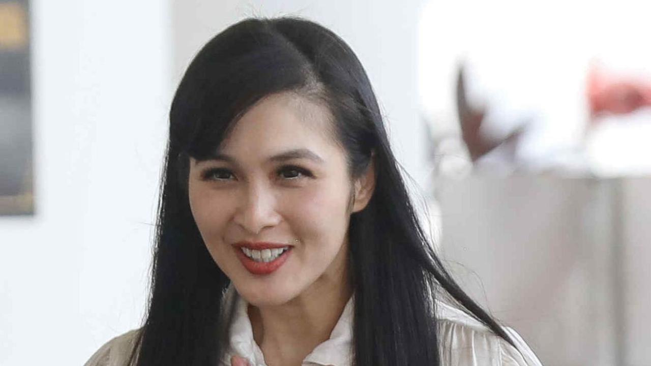 Dalam momen tersebut Sandra Dewi terlihat mengenakan baju putih dipadu bawahan berwarna gelap. Dia terus menebar senyum ketika disapa awak media.&nbsp;Liputan6.com/Herman Zakharia