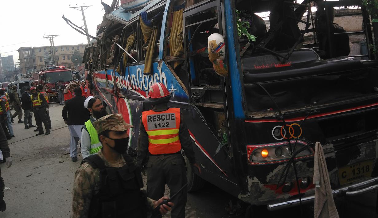 Polisi melakukan penyelidikan di sekitar badan bus usai diserang bom di Peshawar, Pakistan, Rabu (16/3). Bus yang membawa rombongan pegawai pemerintah ini menewaskan setidaknya 10 orang dan 27 lainnya terluka. (AFP / A Majeed)