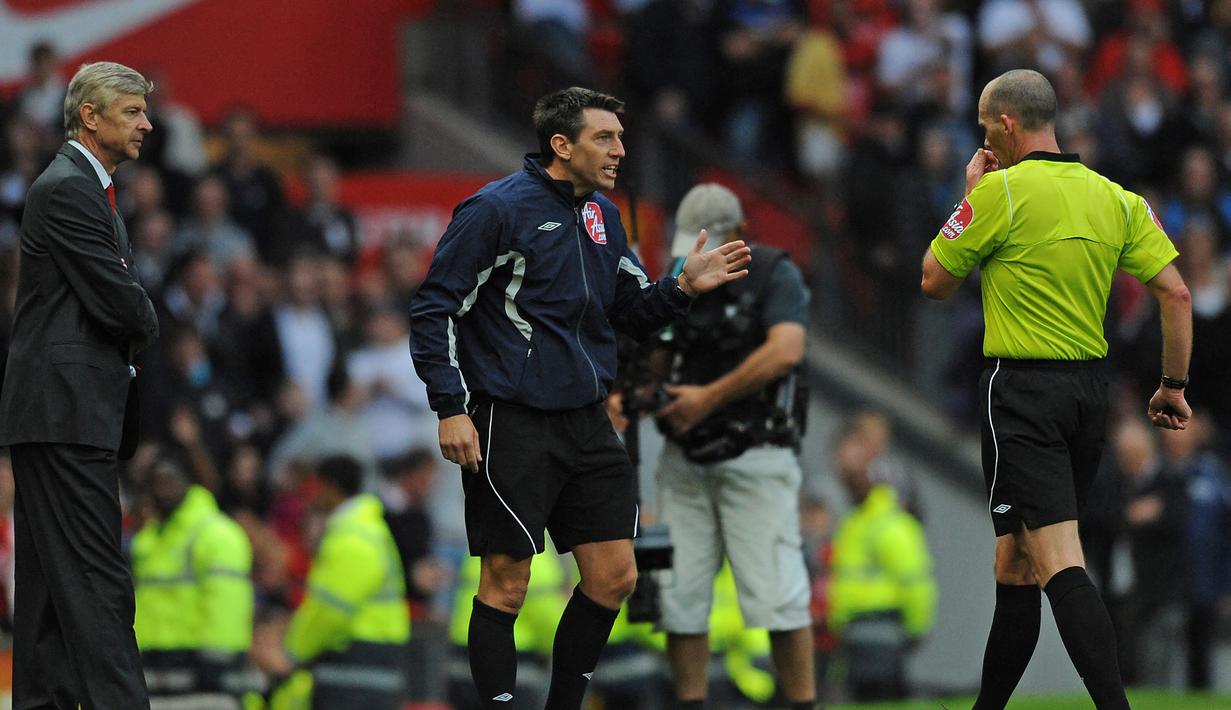 Manchester United vs Arsenal. (29/8/2009). Wasit Mike Dean (kanan) menghampiri manajer tim Arsenal, Arsene Wenger untuk memberi kartu merah dan mengusirnya ke tribun usai mendapat masukan dari ofisial keempat, Lee Probert. (AFP/Paul Ellis)