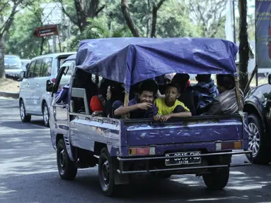 Sejumlah warga menggunakan mobil bak terbuka dengan beratapkan terpal di Jakarta, Minggu (19/7/2015). Meskipun membahayakan, mobil pick up menjadi pilihan warga untuk bersilaturahmi saat momen Lebaran. (Liputan6.com/Faizal Fanani)