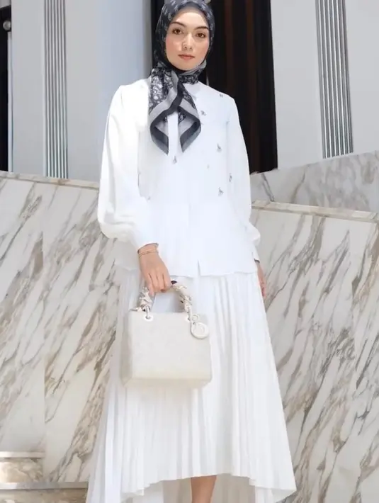 Tampilan clean dan elegan salah satunya bisa ditiru dari gaya Citra Kirana berikut ini. Ia memadukan blazer dan rok a-line serba putih dengan hijab monogram hitam.