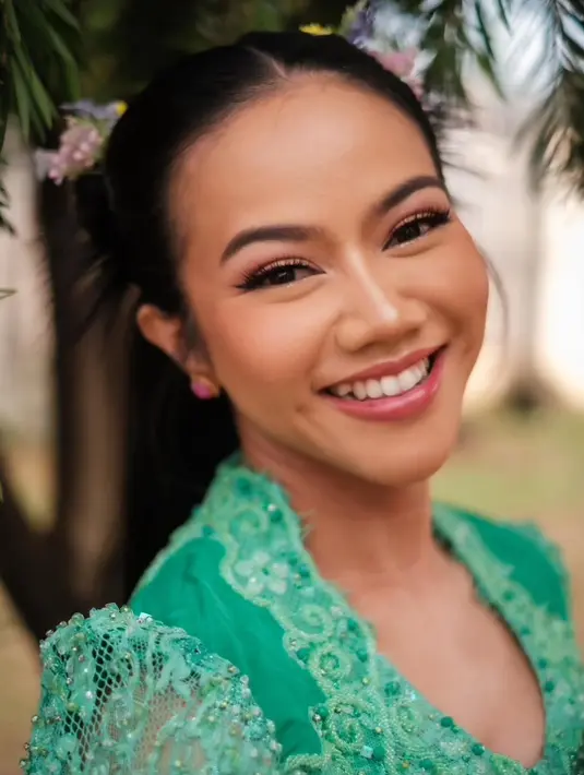 Yura memadukan kebaya brokat berlengan panjang warna tosca dengan detail payet yang cantik bersama bustier pink menyala berhias bordiran bunga-bunga perak.   [@yurayunita].