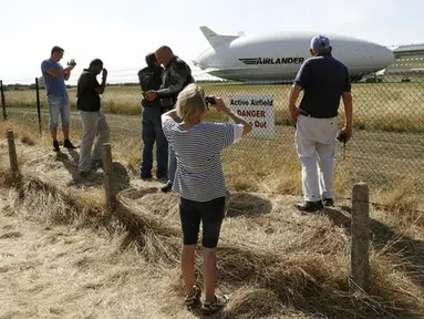 Sejumlah orang mengambil gambar dari pesawat Airlander 10 setelah gagal mendarat di Cardington Airfield, Inggris, Rabu (24/8). Pesawat yang diklaim terbesar di dunia itu rusak karena harus menukik tajam ketika melakukan pendaratan (REUTERS/Darren Staples)