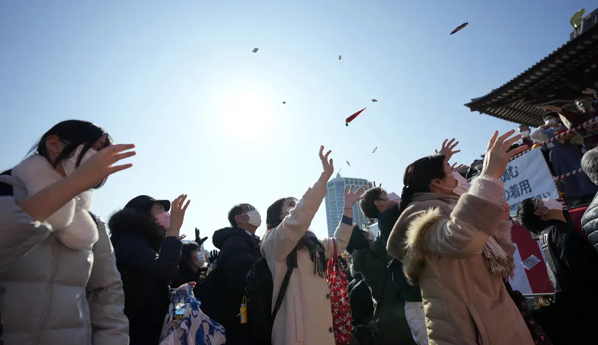 Orang-orang mencoba menangkap kacang keberuntungan yang disebarkan pada "Mame-maki," upacara pelemparan kacang di kuil Buddha Zojoji di Tokyo, 3 Februari 2022. Ritual yang diyakini membawa keberuntungan dan mengusir kejahatan dilakukan setiap tahun untuk menandai awal musim semi. (AP/Eugene Hoshiko)