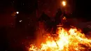 Seorang pria menunggangi kuda melewati api unggun saat festival Luminarias di San Bartolome de Pinares, Spanyol, Jumat (16/1/2020). Tradisi yang sudah berlangsung lebih dari 500 tahun ini bertujuan untuk menyucikan binatang yang identik dengan Santo Antonius. (AP Photo/Manu Fernandez)