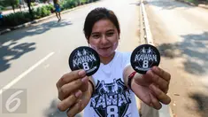 Seorang pemudi menunjukkan PIN berlogo kawan8 saat Car Free Day di kawasan Senayan, Jakarta Minggu (24/7). Mereka juga mengajak masyarakat untuk bisa berlaku adil dalam segala hal. (Liputan6.com/Fery Pradolo)