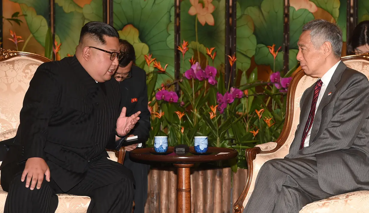 Pemimpin Korea Utara, Kim Jong-un berbincang dengan Perdana Menteri Singapura Lee Hsien Loong di Istana Kepresidenan Singapura, Minggu (10/6). Kim Jong-un dan Donald Trump akan bertemu 12 Juni. (AFP Photo/HO/Kementerian Kominfo Singapura)
