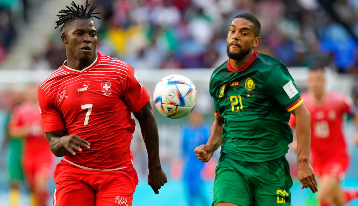 Pemain Swiss Breel Embolo (kiri) mengejar bola dengan pemain Kamerun Jean-Charles Castelletto pada pertandingan sepak bola Grup G Piala Dunia 2022 di Stadion Al Janoub, Al Wakrah, Qatar, Kamis (24/11/2022). Swiss mengalahkan Kamerun dengan skor 1-0. (AP Photo/Luca Bruno)