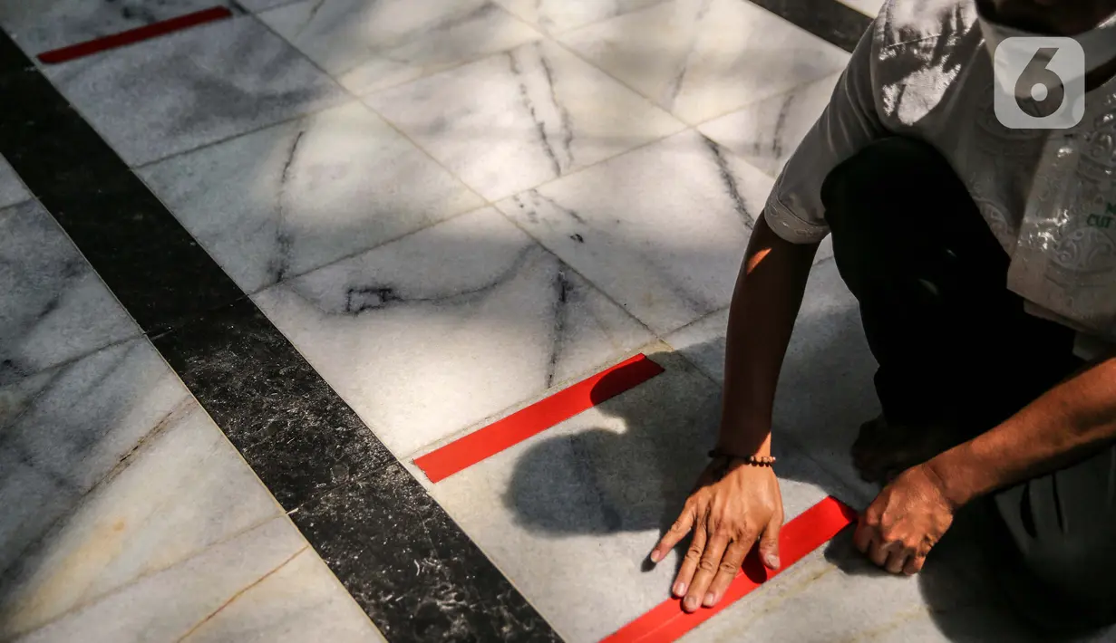 Petugas memasang tanda batas shaf di Masjid Cut Meutia, Jakarta, Kamis (30/7/2020). Masjid Cut Meutia akan menggelar Salat Idul Adha esok hari dengan menerapkan protokol kesehatan pencegahan Covid-19. (Liputan6.com/Faizal Fanani)