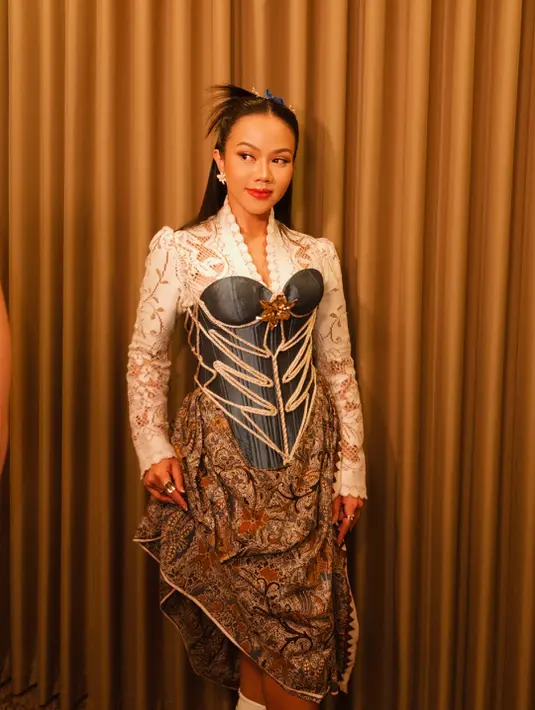 Sementara dalam tampilan lainnya, Yura tampil lebih eksperimental. Ia mengenakan kebaya kutu baru putih transparan dengan bordiran halus, dipadukan dengan bustier denim berstruktur korset lengkap dengan tali-temali dekoratif. [@yurayunita].