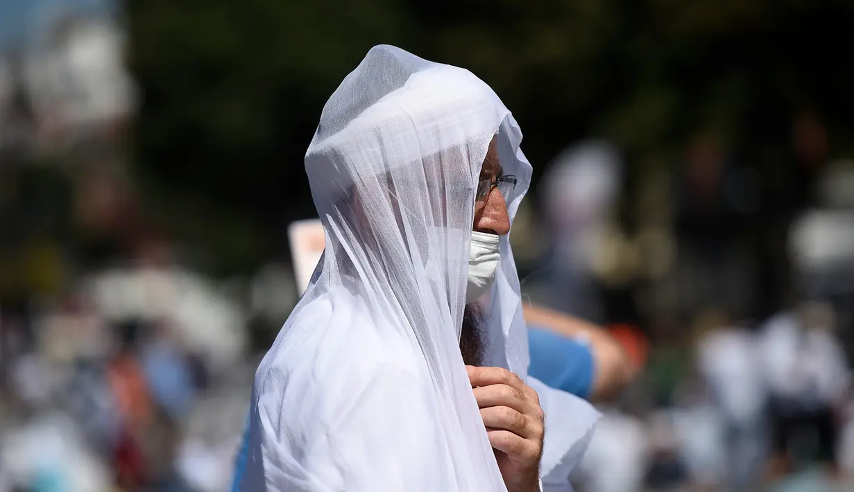 Jemaah mengenakan masker untuk menghindari penyebaran COVID-19 saat menunggu di distrik bersejarah Sultanahmet, dekat Hagia Sophia, Istanbul, Turki, Jumat (24/7/2020). Umat muslim melaksanakan salat Jumat pertama di Hagia Sophia dalam 86 tahun terakhir. (AP Photo/Yasin Akgul)