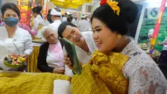 Seorang perempuan bercermin untuk melihat kondisi giginya saat ritual potong gigi massal di Pura Giri Kusuma, Kota Bogor, Minggu (9/7/2023). (merdeka.com/Arie Basuki)