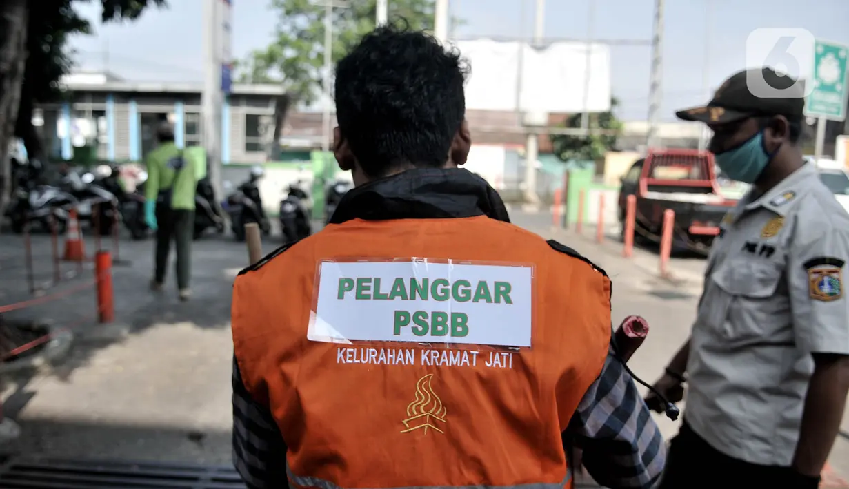 Seorang warga mengenakan rompi pelanggar PSBB akibat tidak mengenakan masker di area Pasar Kramat Jati, Jakarta, Rabu (17/6/2020). (merdeka.com/Iqbal S. Nugroho)