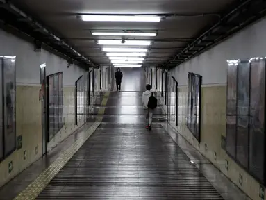 Komuter melewati terowongan menuju stasiun kereta bawah tanah di Beijing, China, Senin (17/2/2020). Wabah virus corona atau COVID-19 menyebabkan beberapa kota besar di China menjadi sepi, salah satunya Beijing. (AP Photo/Andy Wong)