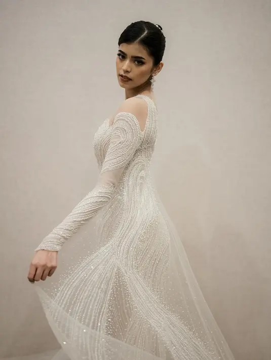 Dalam unggahan yang dibagikan sang desainer di Instagram, terlihat Jharna yang begitu  menawan dalam balutan gaun pengantin berwarna putih. Detail manik-manik putih yang menghiasi seluruh gaun membuat penampilan Jharna semakin elegan. [@hiantjen]