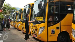 Petugas mengelap bus sekolah di Terminal Pasar Minggu, Jakarta, Senin (26/10). Gubernur DKI Basuki Tjahaja Purnama berencana menghapus keberadaan bus sekolah. Sebagai gantinya, pelajar akan digratiskan naik Transjakarta. (Liputan6.com/Gempur M Surya)