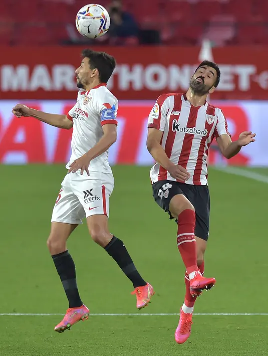 Gelandang Sevilla, Jesus Navas berebut bola udara dengan bek Athletic Bilbao,Mikel Balenziaga pada pertandingan La Liga Spanyol di stadion Ramon Sanchez Pizjuan, Seville, Selasa (4/5/2021). Kekalahan atas Bilbao, membuat Sevilla gagal mendekati tiga tim teratas Liga Spanyol. (AFP/Cristina Quicler)