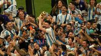 Pemain Argentina Lionel Messi (tengah) memegang trofi juara saat merayakan bersama para penggemar setelah Argentina mengalahkan Prancis pada pertandingan sepak bola final Piala Dunia 2022 di Stadion Lusail, Lusail, Qatar, 18 Desember 2022. Argentina menang 4-2 dalam adu penalti setelah pertandingan berakhir imbang 3 -3. (AP Photo/Francisco Seco)