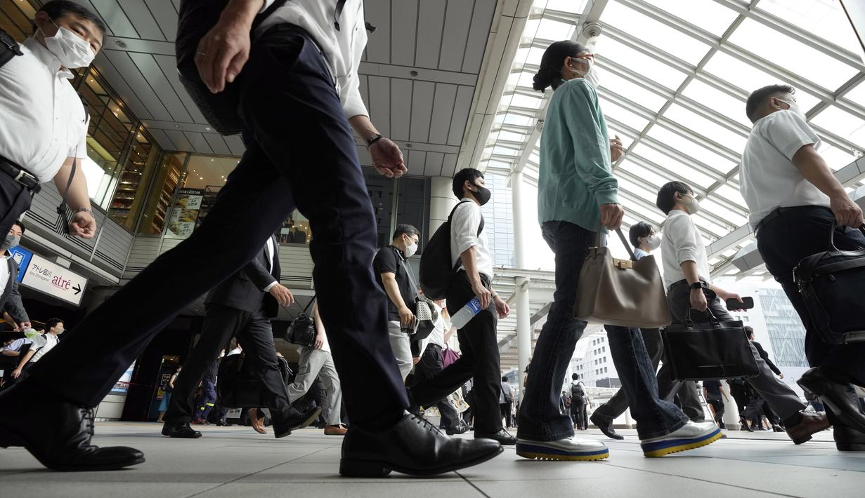 Komuter yang mengenakan masker berjalan di lorong selama jam sibuk di Stasiun Shinagawa, Tokyo, Senin (12/7/2021). Otoritas Jepang menempatkan Tokyo di bawah keadaan darurat Covid-19 keempat sebagai upaya menahan lonjakan kasus infeksi virus Corona dari Senin hingga 22 Agustus. (AP /Eugene Hoshiko)