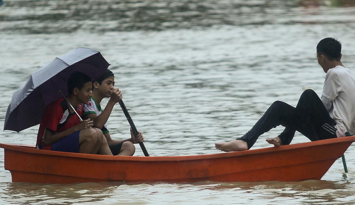 Sejumlah remaja menggunakan kano untuk melewati banjir di Rantau Panjang, timur laut Malaysia, Selasa (3/1). Akibat hujan lebat yang turun terus menerus selama empat hari di Malaysia, 5.000 warga terpaksa dievakuasi. (AFP PHOTO/STR/Malaysia OUT)