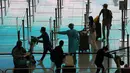<p>Pekerja mengenakan pakaian pelindung mengarahkan penumpang yang tiba dari Manila untuk karantina di bandara internasional Hong Kong, Jumat (1/4/2022). Penerbangan mulai mendarat di Hong Kong Jumat (1/4) setelah pihak berwenang mencabut larangan tindakan COVID-19. (AP Photo/Kin Cheung)</p>