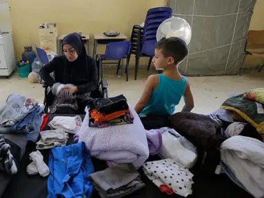 Seorang wanita Lebanon yang mengungsi melipat pakaian di dalam ruang kelas di sebuah sekolah yang menampung para pengungsi Lebanon, di kota Deir Ammar, Lebanon utara, pada 17 Oktober 2024. (Ibrahim Chalhoub/AFP)