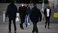 Orang-orang yang memakai masker berjalan di luar Stasiun Flinders Street di Melbourne, Kamis (23/7/2020). Sebagian penduduk kota terpadat kedua di Australia, Melbourne, mematuhi undang-undang baru yang mewajibkan pemakaian masker. (James Ross / AAP Image via AP)