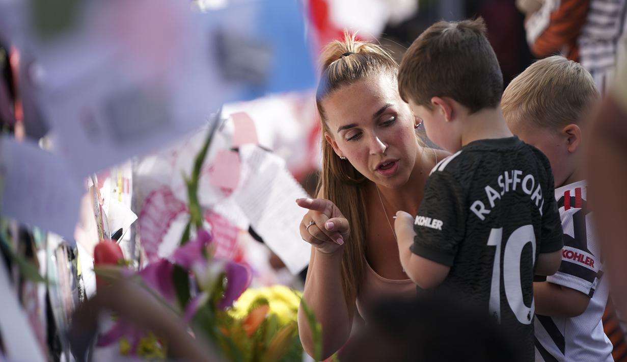Seorang ibu mengajari anaknya untuk menempelkan pesan saat mengikuti aksi antirasisme di depan mural Marcus Rashford di Withingston, Manchester. (Foto:AP/Jon Super)
