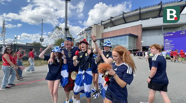 Suporter Skotlandia atau Tartan Army bernyanyi dan meneriakkan yel-yel di area fanzone Gillette Stadium, Foxborough, Amerika Serikat, Jumat (19/6/2026), menjelang laga melawan Maroko pada Piala Dunia 2026. Mereka mengenakan kilt tradisional, membawa bendera Saltire, serta berbagai atribut khas Skotlandia. (KLY Sports/Hery Kurniawan)