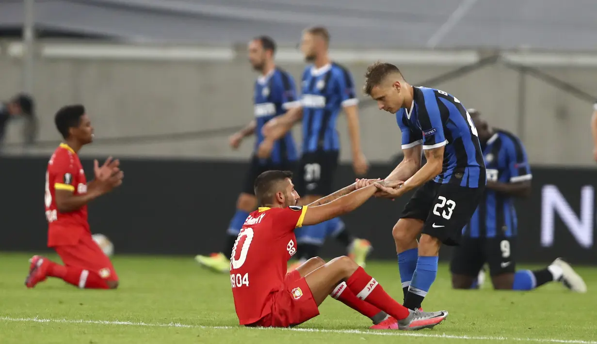 Pemain Inter Milan Nicolo Barella (kanan) membantu pemain Bayer Leverkusen Kerem Demirbay berdiri usai perempat final Liga Europa di Duesseldorf Arena,  Dusseldorf, Jerman, Senin (10/8/2020). Inter Milan melaju ke semifinal usai mengalahan Bayer Leverkusen. (Dean Mouhtaropoulos, Pool Photo via AP)