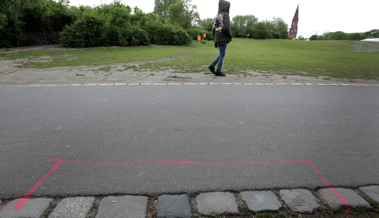 Pejalan kaki melintas dekat zona pink yang disebut 'Area Pengedar Obat' di Taman Goerlitzer, Berlin, 9 Mei 2019. Nantinya, para bandar hanya boleh bertransaksi di dalam zona berupa coretan kotak dengan cat semprot berwarna pink itu saja. (AP Photo/Michael Sohn)