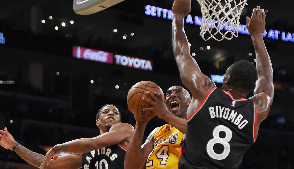 Pemain Los Angeles Lakers, Kobe Bryant berusaha memasukan bola dari kawalan dua pemain Toronto Raptors DeMar DeRozan dan Bismack Biyombo selama pertandingan NBA di Los Angeles Pada 20 November 2015. (AP Photo/Mark J. Terrill)
