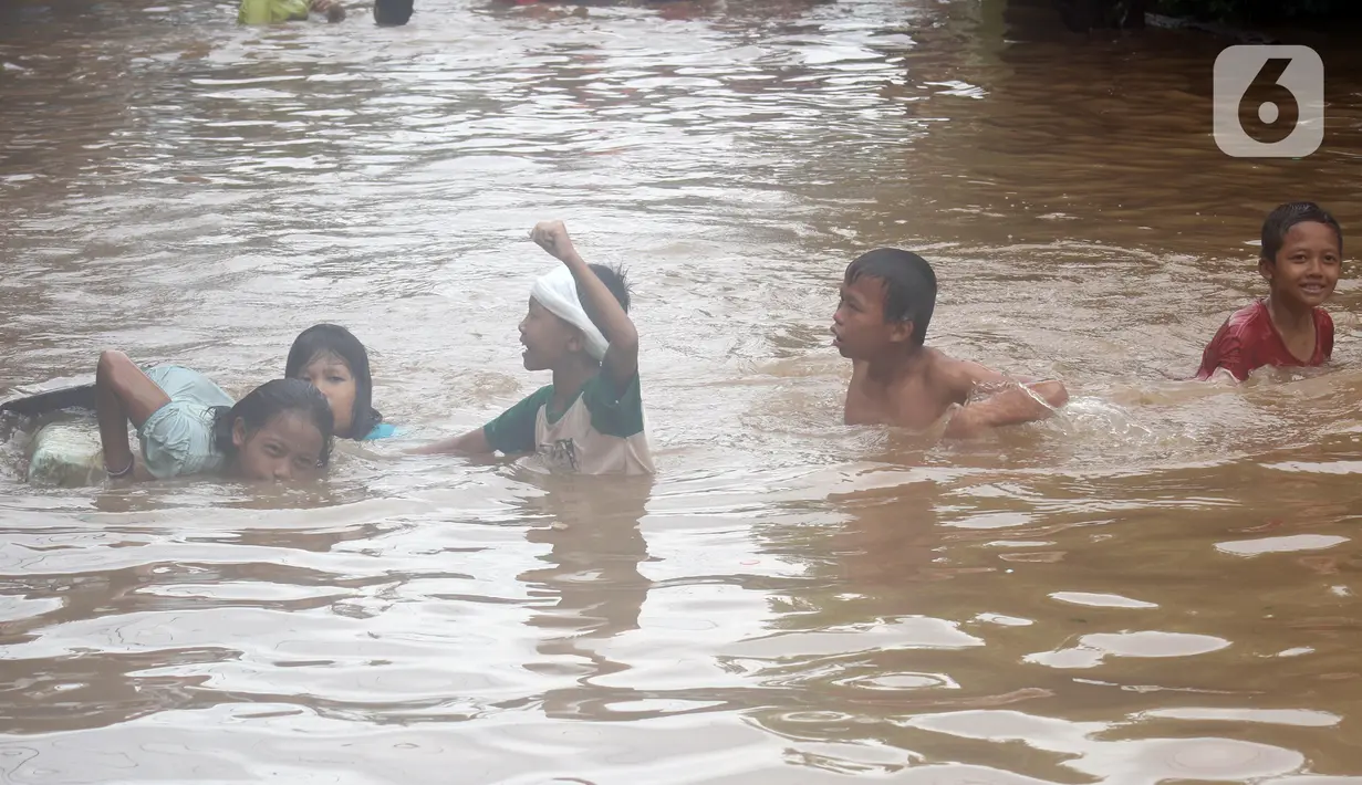 Anak-anak berenang di salah satu gang di Kawasan Rawajati yang tergenang banjir, Jakarta, Rabu Rabu (1/1/2020). Hujan yang mengguyur Jakarta sejak Selasa sore (31/12/2019) mengakibatkan banjir di sejumlah titik di Jakarta. (Liputan6.com/Helmi Fithriansyah)