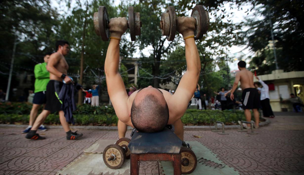 Seorang warga berlatih beban di Danau Hoan Kiem, Hanoi, Vietnam, (23/11/2015). (EPA/Luong Thai Linh)