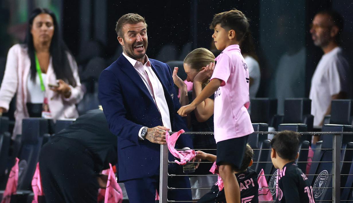 <p>Reaksi pemilik klub Inter Miami, David Beckham (kiri) saat anak dari Lionel Messi dan Sergio Busquets mencipratkan air sebelum laga Inter Miami melawan Orlando City pada laga lanjutan MLS Amerika di DRV PNK Stadium, Florida, Amerika Serikat, 2 Agustus 2023 waktu setempat. (AFP/Getty Images/Hector Vivas)</p>