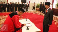 Hakim Mahkamah Konstitusi (MK) yang baru, Saldi Isra disaksikan Presiden Joko Widodo  menandatangani dokumen pelantikan sebagai Hakim MK di Istana Negara, Jakarta, Selasa (11/4). Saldi Isra menggantikan Patrialis Akbar. (Liputan6.com/Angga Yuniar)